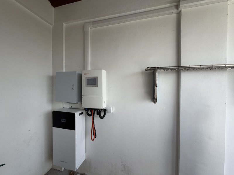 A hybrid inverter, a protection box and a floor-standing battery on a white wall, cable trunking run along the wall and ceiling.