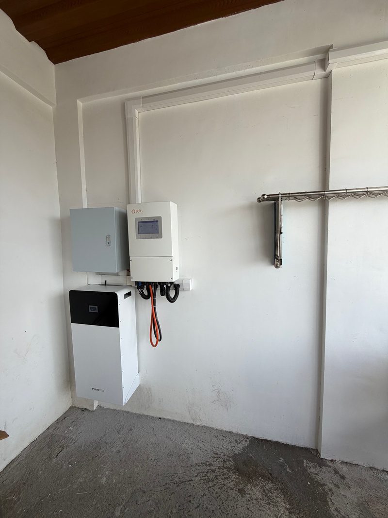 Wide view of the equipment corner, trunking dropping from the ceiling to the inverter.