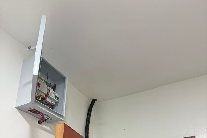A DC isolator enclosure mounted high on the wall, flexible conduit running into the ceiling.